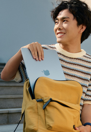 一名學(xué)生坐在外面。他從書(shū)包里拿出一臺(tái)封閉的 MacBook。