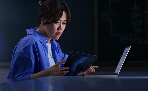 照片展示一位女生坐在書(shū)桌前用著 MacBook Air，同時(shí)一手拿著一張 X 光片。