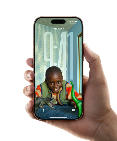 一只手拿著一部 iPhone，展示全新的 Liquid Glass 設(shè)計(jì)。鎖定屏幕上的時(shí)間數(shù)字，會(huì)根據(jù)背景畫(huà)面靈活調(diào)整。
